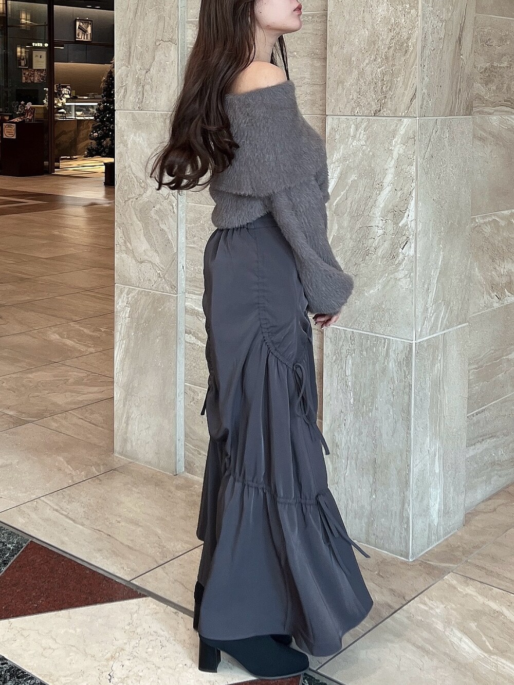 ブラウン系のニット/セーター、グレー系のスカート、その他のブーツを着用したレディースの冬コーディネートの8枚目の写真