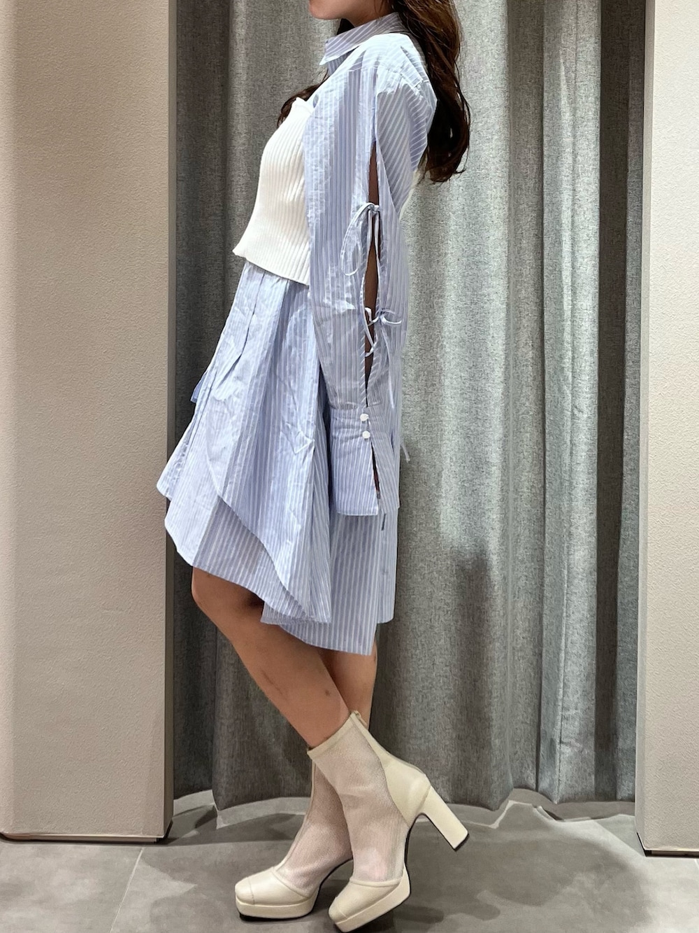 ホワイト系のキャミソール、ブルー系のシャツワンピース、ホワイト系のブーツを着用したレディースの冬コーディネートの5枚目の写真