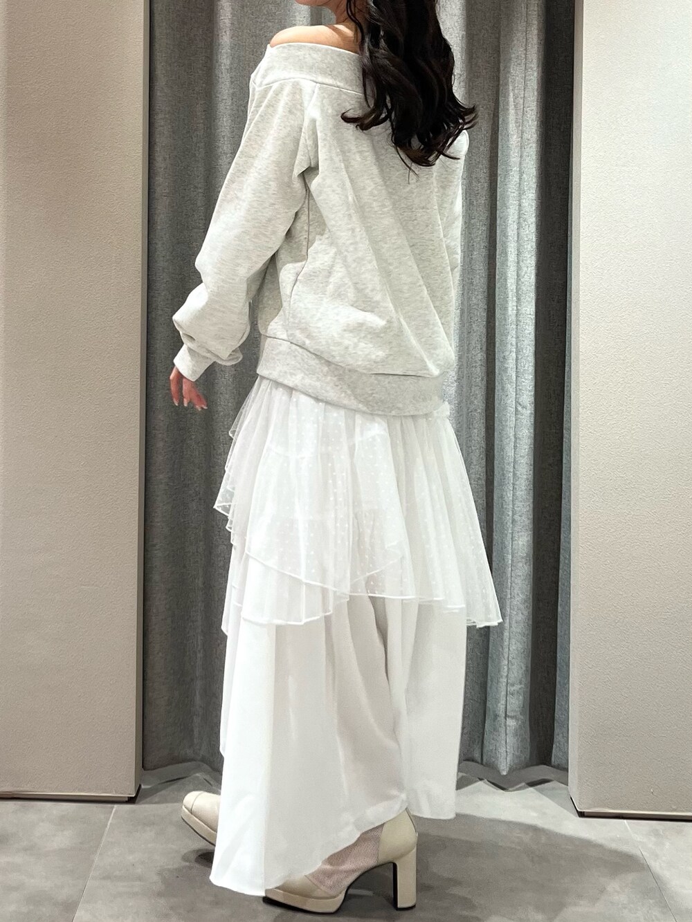 グレー系のスウェット、ホワイト系のスカート、ホワイト系のブーツを着用したレディースの春コーディネートの6枚目の写真