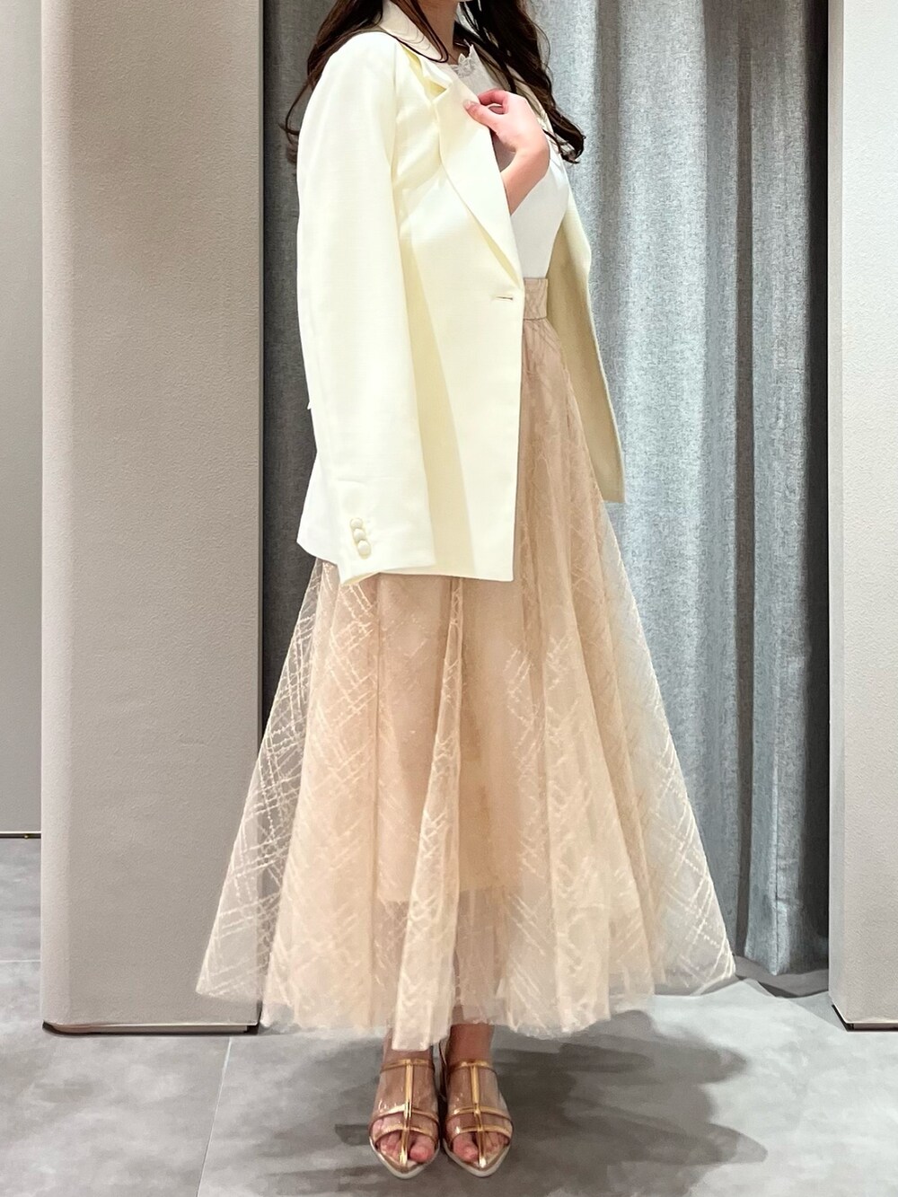 ホワイト系のニット/セーター、ホワイト系のテーラードジャケット、ベージュ系のスカートを着用したレディースの春コーディネートの6枚目の写真