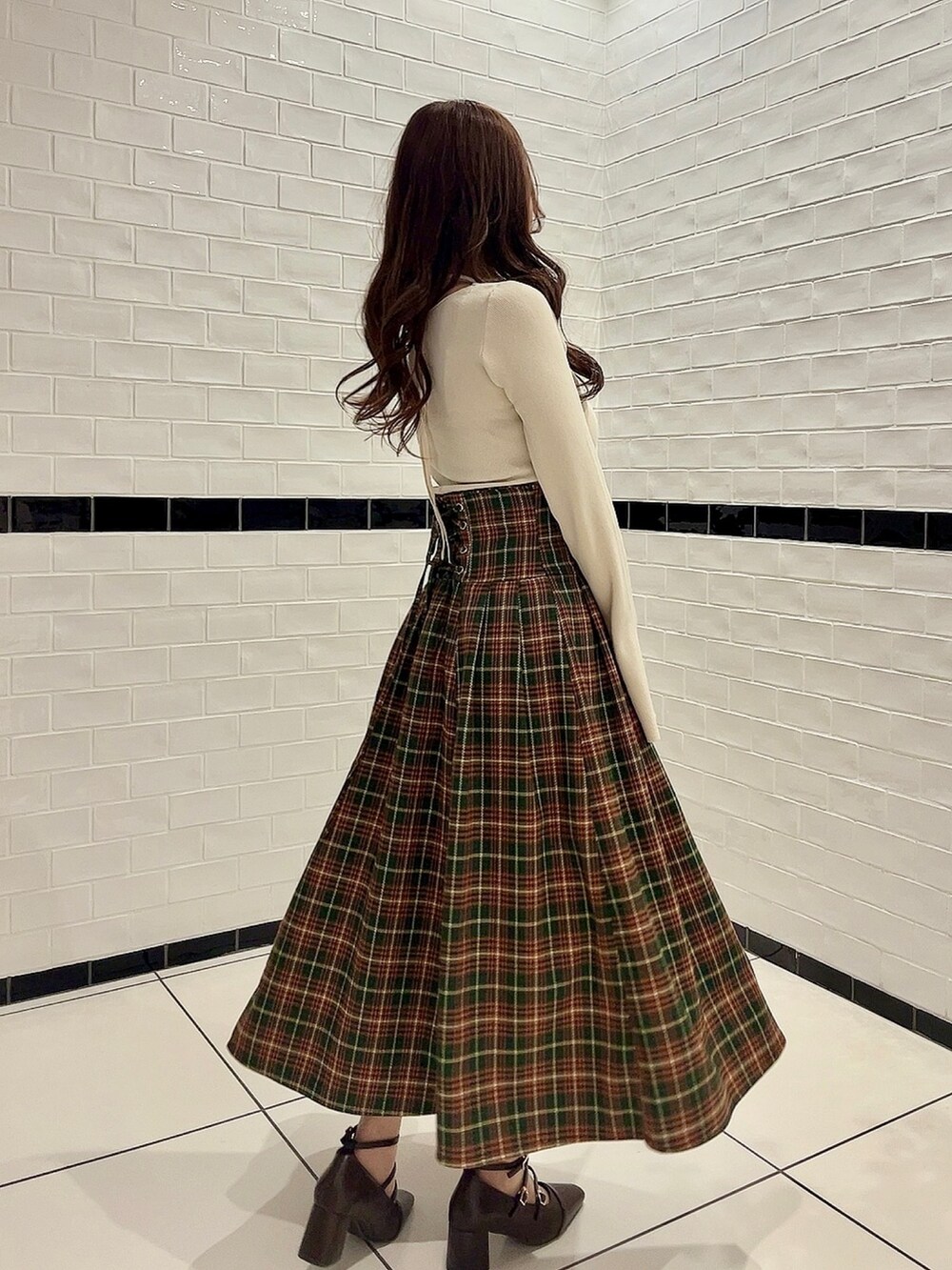 ホワイト系のニット/セーター、グリーン系のスカート、ブラウン系のパンプスを着用したレディースの冬コーディネートの2枚目の写真