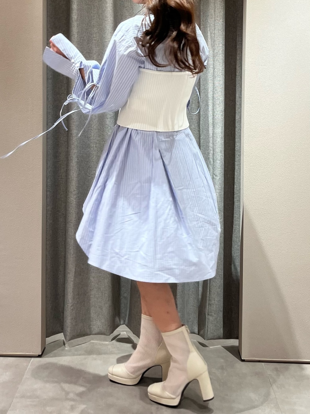 ホワイト系のキャミソール、ブルー系のシャツワンピース、ホワイト系のブーツを着用したレディースの冬コーディネートの8枚目の写真