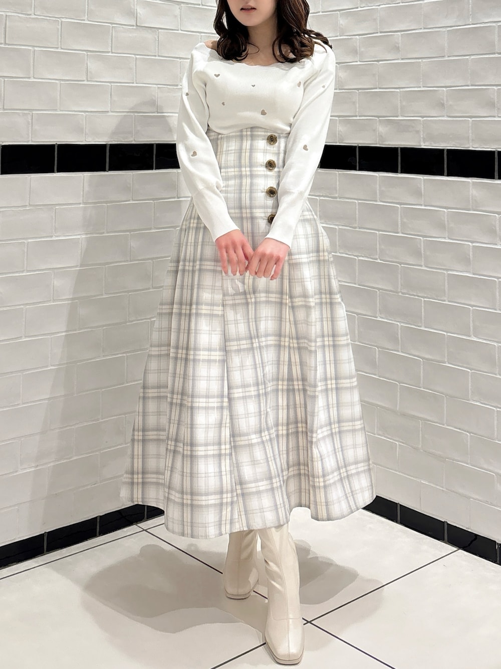 ホワイト系のニット/セーター、ホワイト系のスカート、ホワイト系のブーツを着用したレディースの冬コーディネートの2枚目の写真