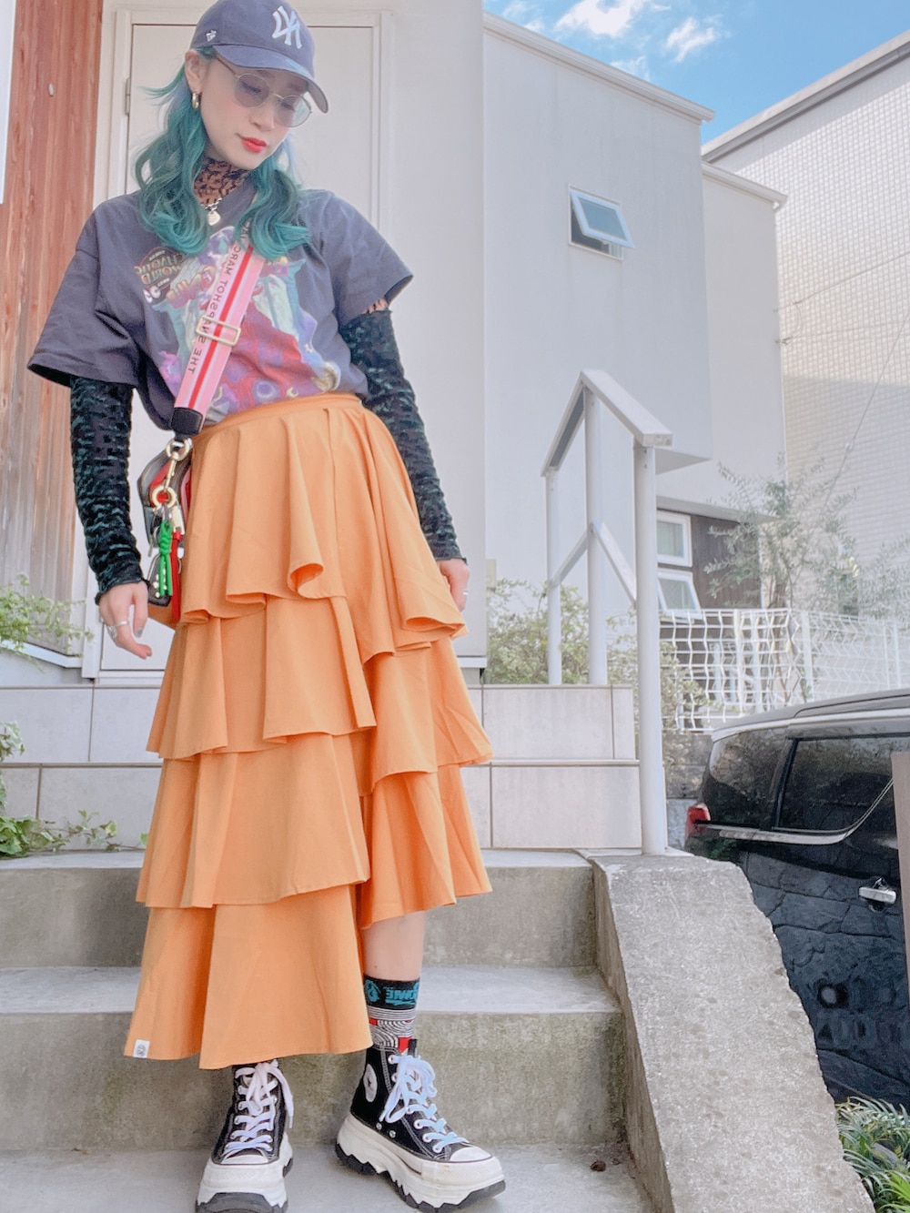 オレンジ系のスカート、ブラック系のスニーカー、オレンジ系のTシャツ/カットソーを着用したレディースの秋コーディネートの2枚目の写真