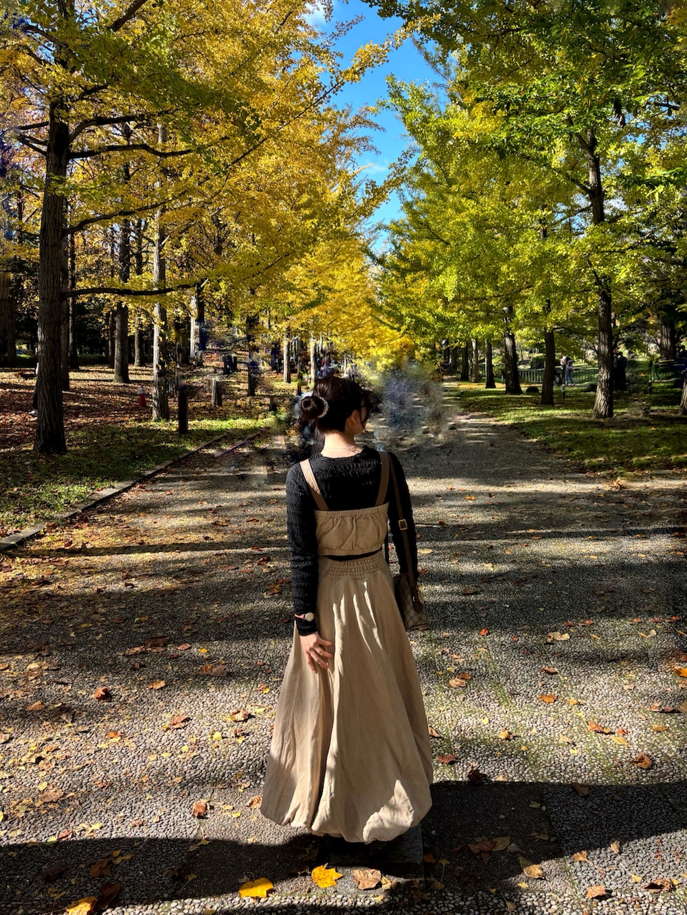 ベージュ系のスニーカー、ブラック系のTシャツ/カットソー、ベージュ系のデニムスカートを着用したレディースの秋コーディネートの2枚目の写真