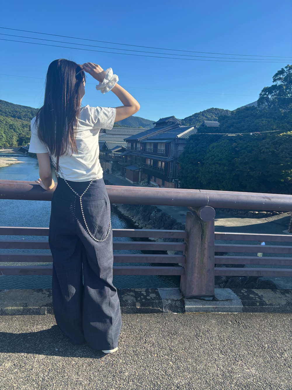 ホワイト系のTシャツ/カットソー、ブラウン系のショルダーバッグ、ブルー系のスラックスを着用したレディースの夏コーディネートの2枚目の写真