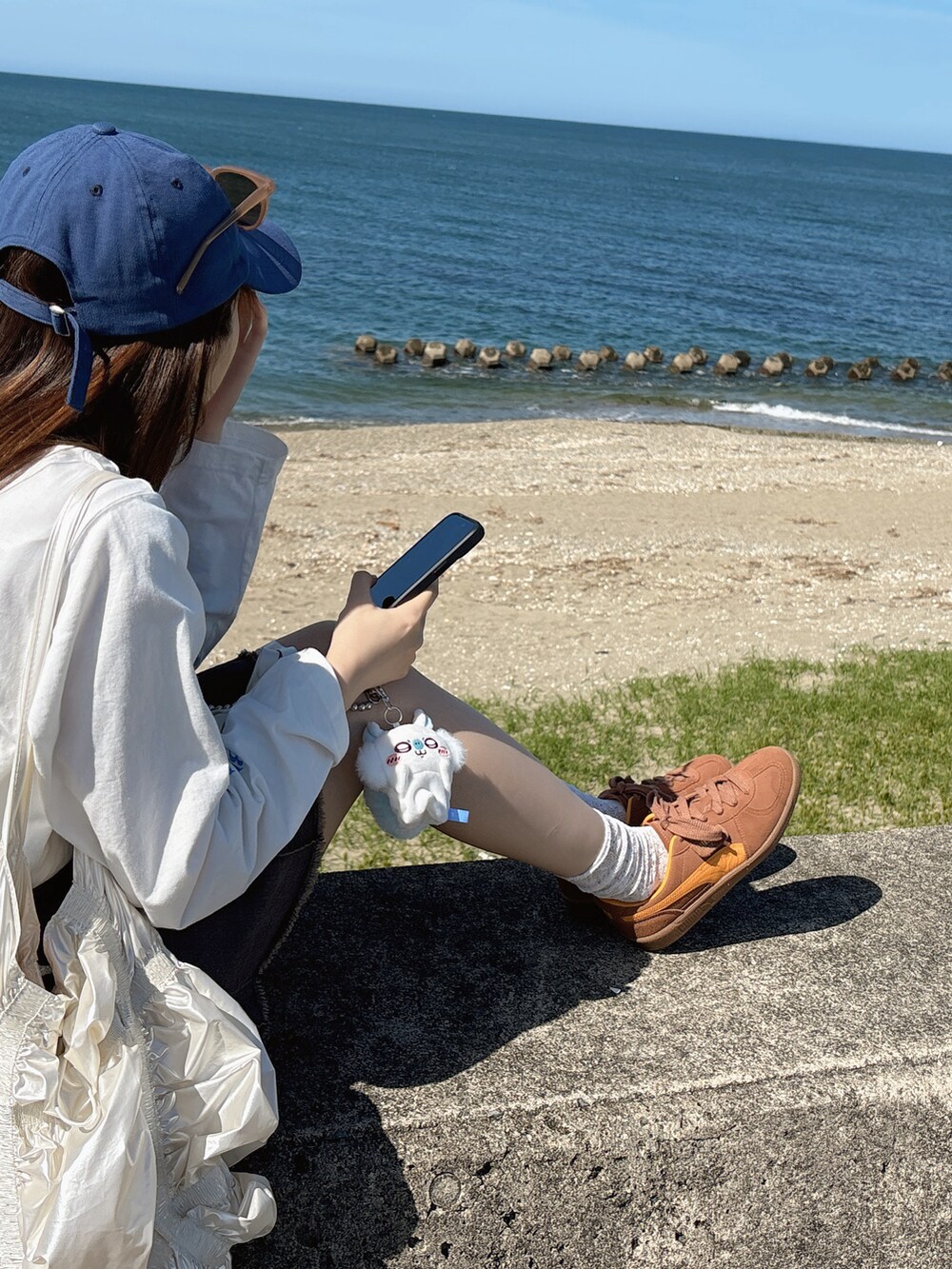 ホワイト系のTシャツ/カットソー、グレー系のデニムスカート、ホワイト系のショルダーバッグを着用したレディースの春コーディネートの2枚目の写真