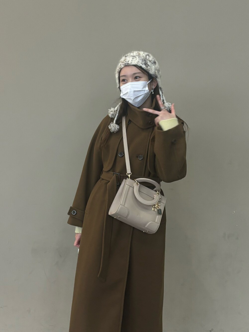 ベージュ系のショルダーバッグを着用したレディースの冬コーディネートの2枚目の写真