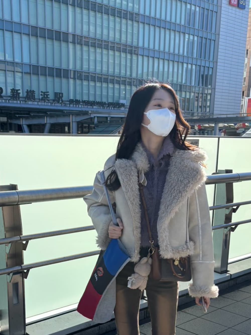 ホワイト系のムートンコート、ブラウン系のデニムパンツ、イエロー系のブーツを着用したレディースの冬コーディネートの2枚目の写真