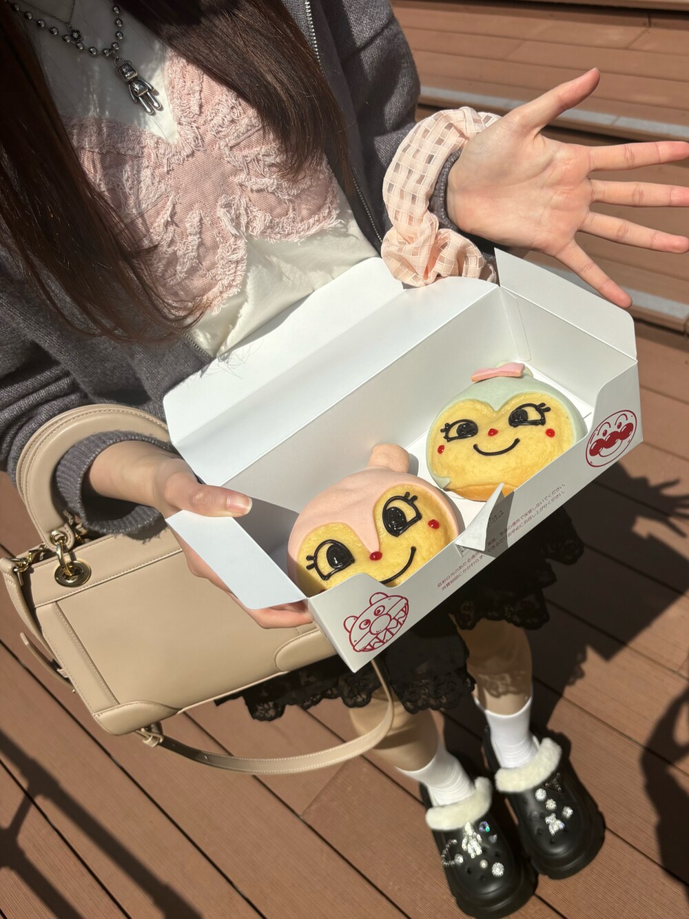 グレー系のニット/セーター、ホワイト系のTシャツ/カットソー、ベージュ系のショルダーバッグを着用したレディースの春コーディネートの2枚目の写真