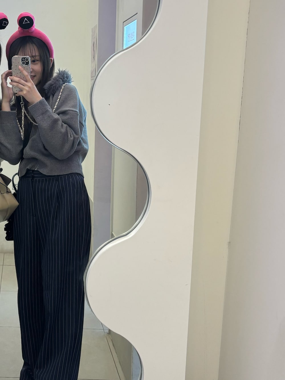 グレー系のニット/セーター、ブラック系のショルダーバッグ、ブルー系のスラックスを着用したレディースの春コーディネートの3枚目の写真