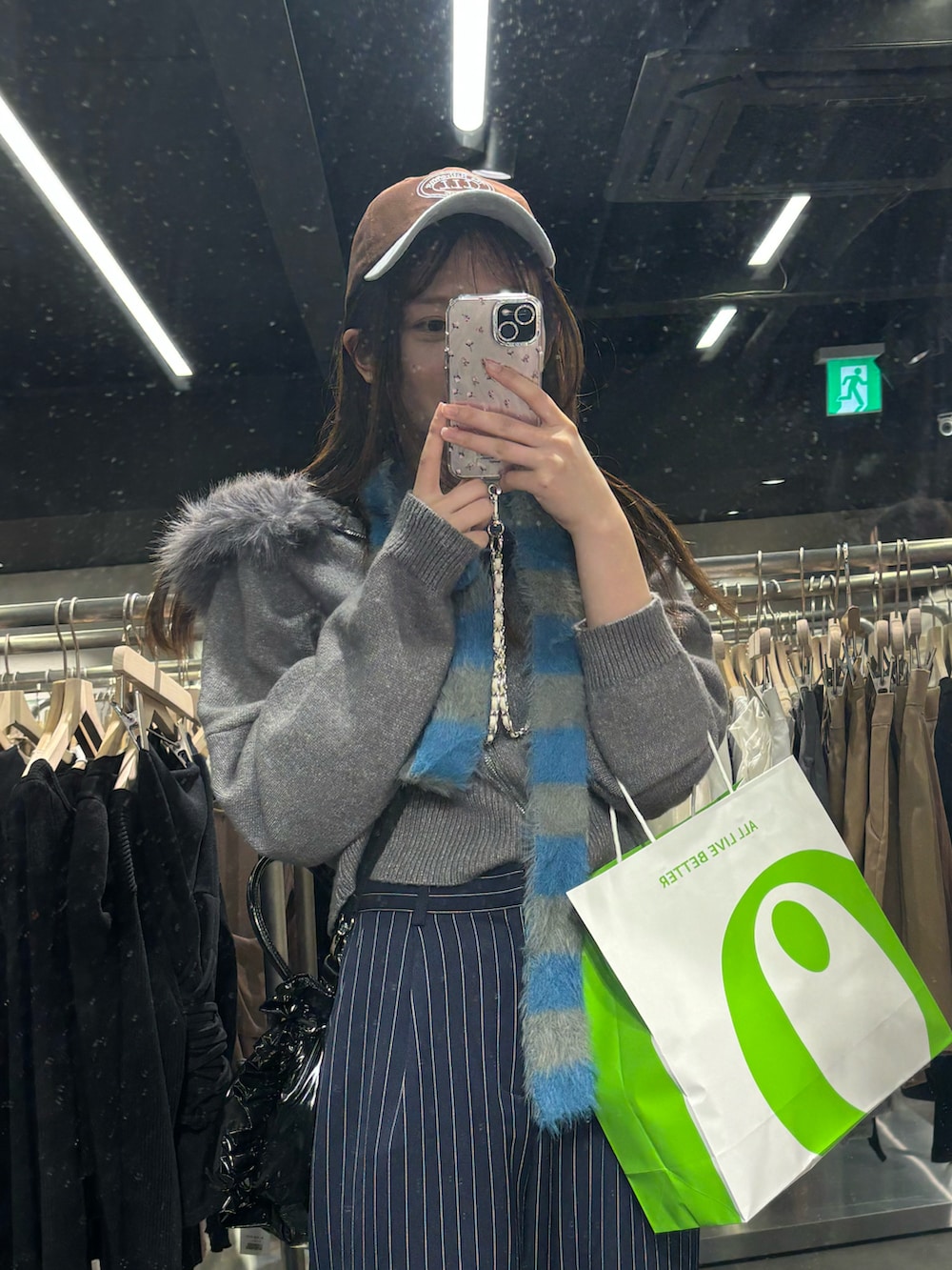 グレー系のニット/セーター、ブラック系のショルダーバッグ、ブルー系のスラックスを着用したレディースの春コーディネートの2枚目の写真