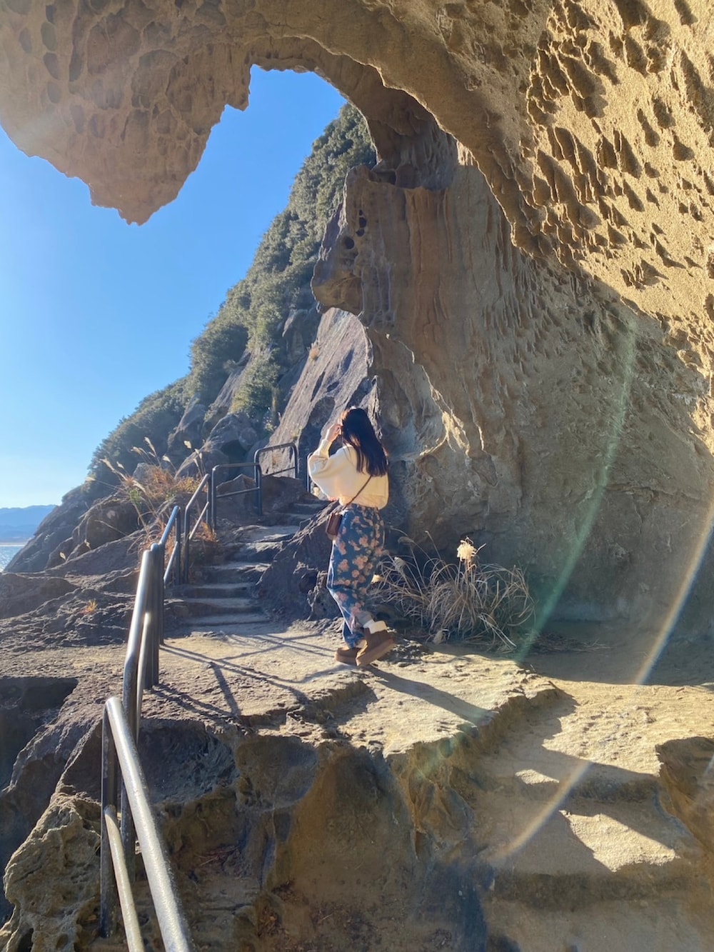 イエロー系のブーツ、ブラウン系のショルダーバッグ、ホワイト系のニット/セーターを着用したレディースの冬コーディネートの2枚目の写真