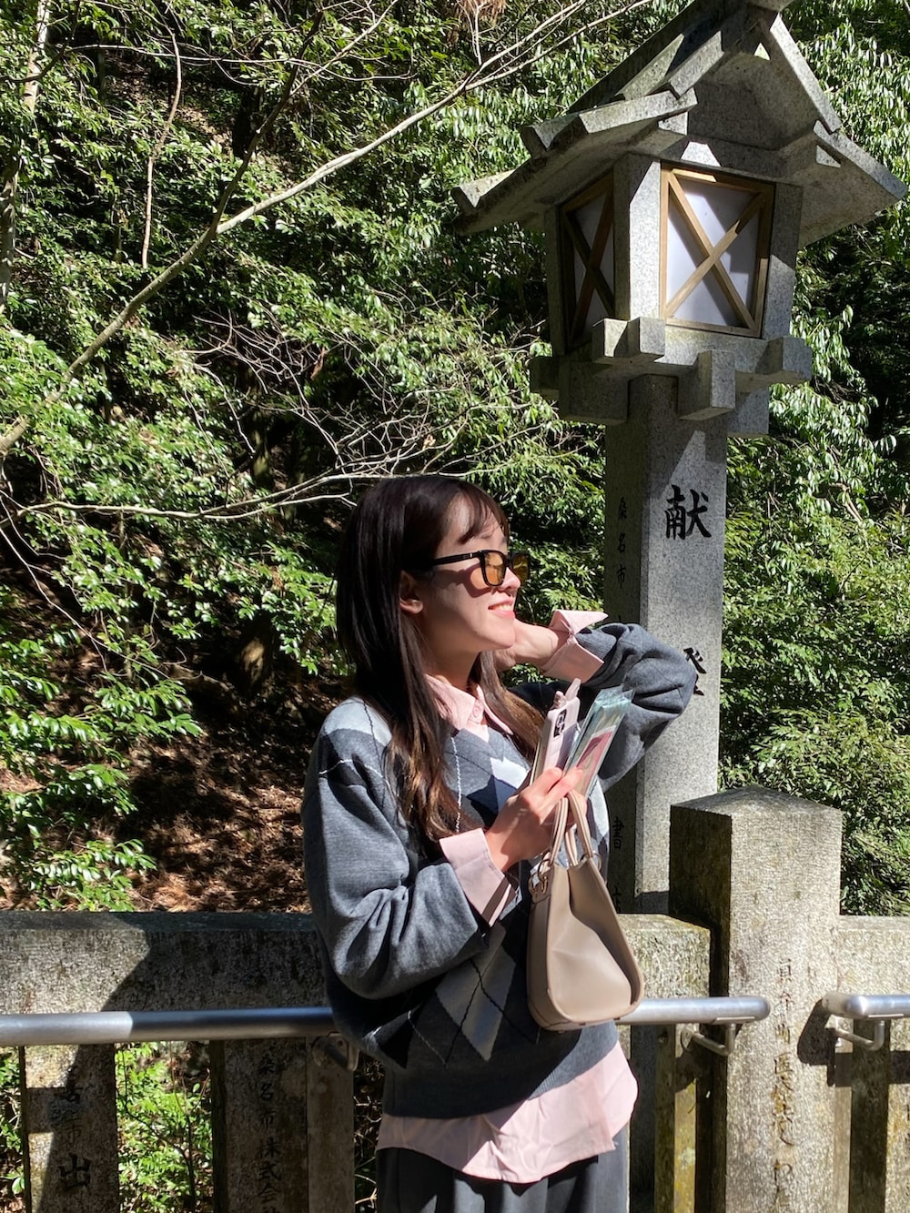 グレー系のニット/セーター、ピンク系のシャツ/ブラウス、ベージュ系のショルダーバッグを着用したレディースの春コーディネートの2枚目の写真