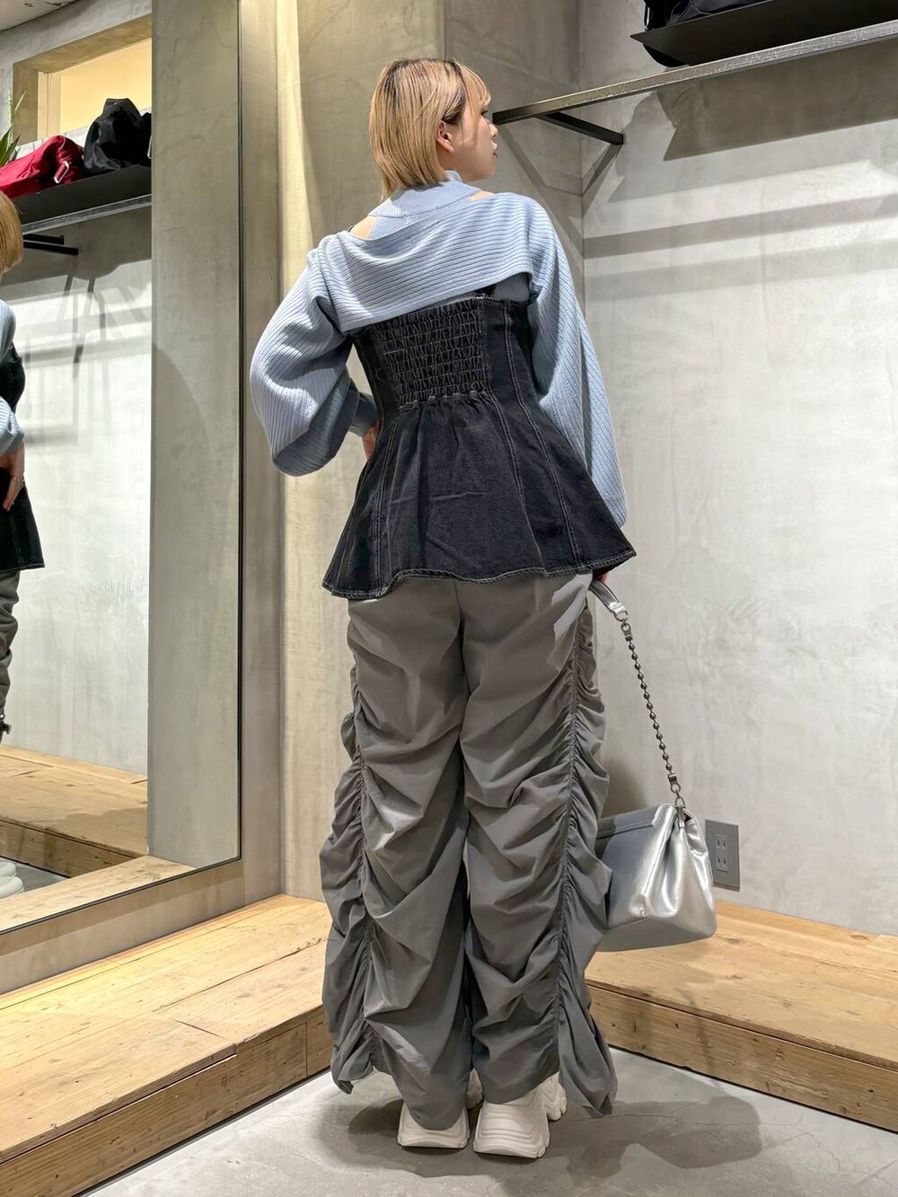 シルバー系のショルダーバッグ、ブラック系のベスト、ホワイト系のスニーカーを着用したレディースの春コーディネートの4枚目の写真