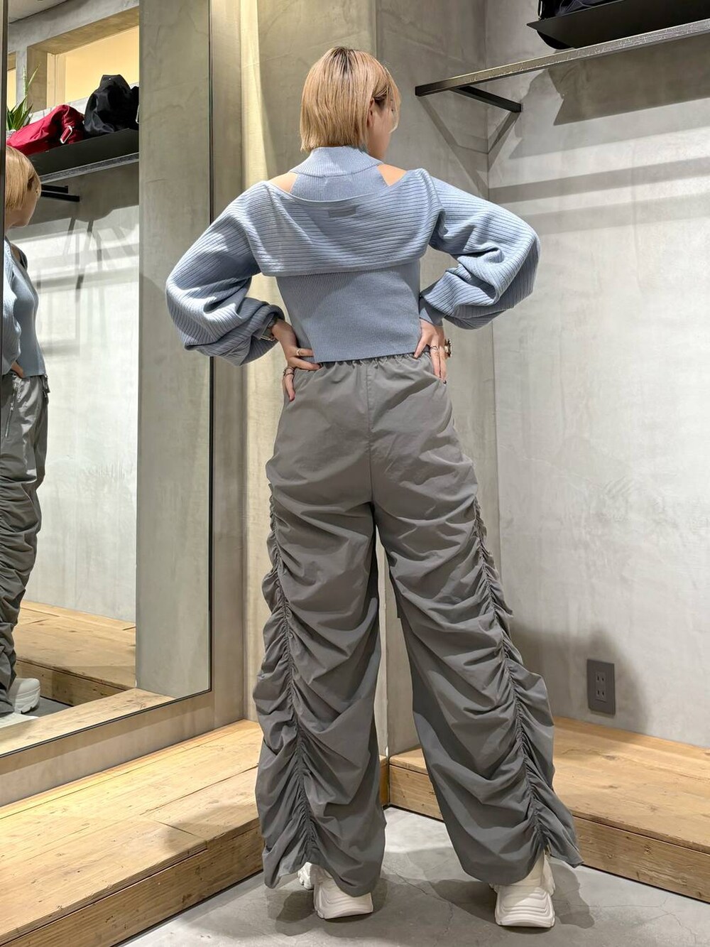 グレー系のその他パンツ、ホワイト系のスニーカー、ブルー系のニット/セーターを着用したレディースの春コーディネートの5枚目の写真