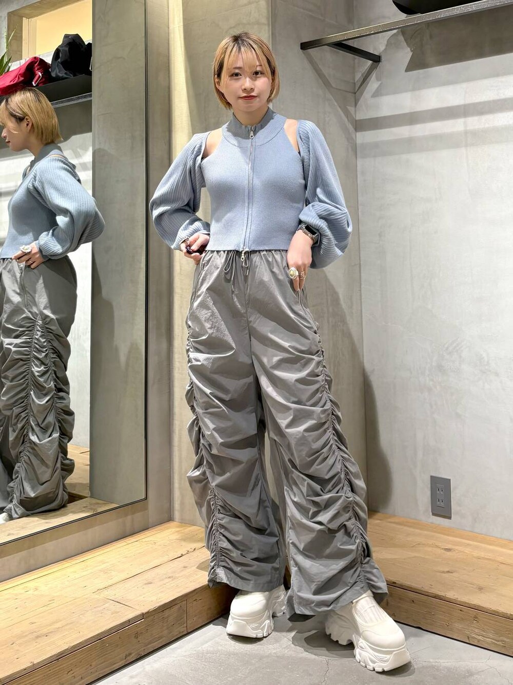 グレー系のその他パンツ、ホワイト系のスニーカー、ブルー系のニット/セーターを着用したレディースの春コーディネートの3枚目の写真