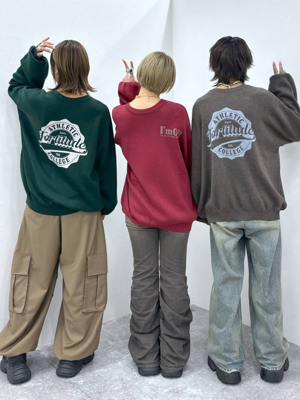 ブラック系のスニーカー、ブラック系のデニムパンツ、レッド系のニット/セーターを着用したレディースの秋コーディネートの2枚目の写真