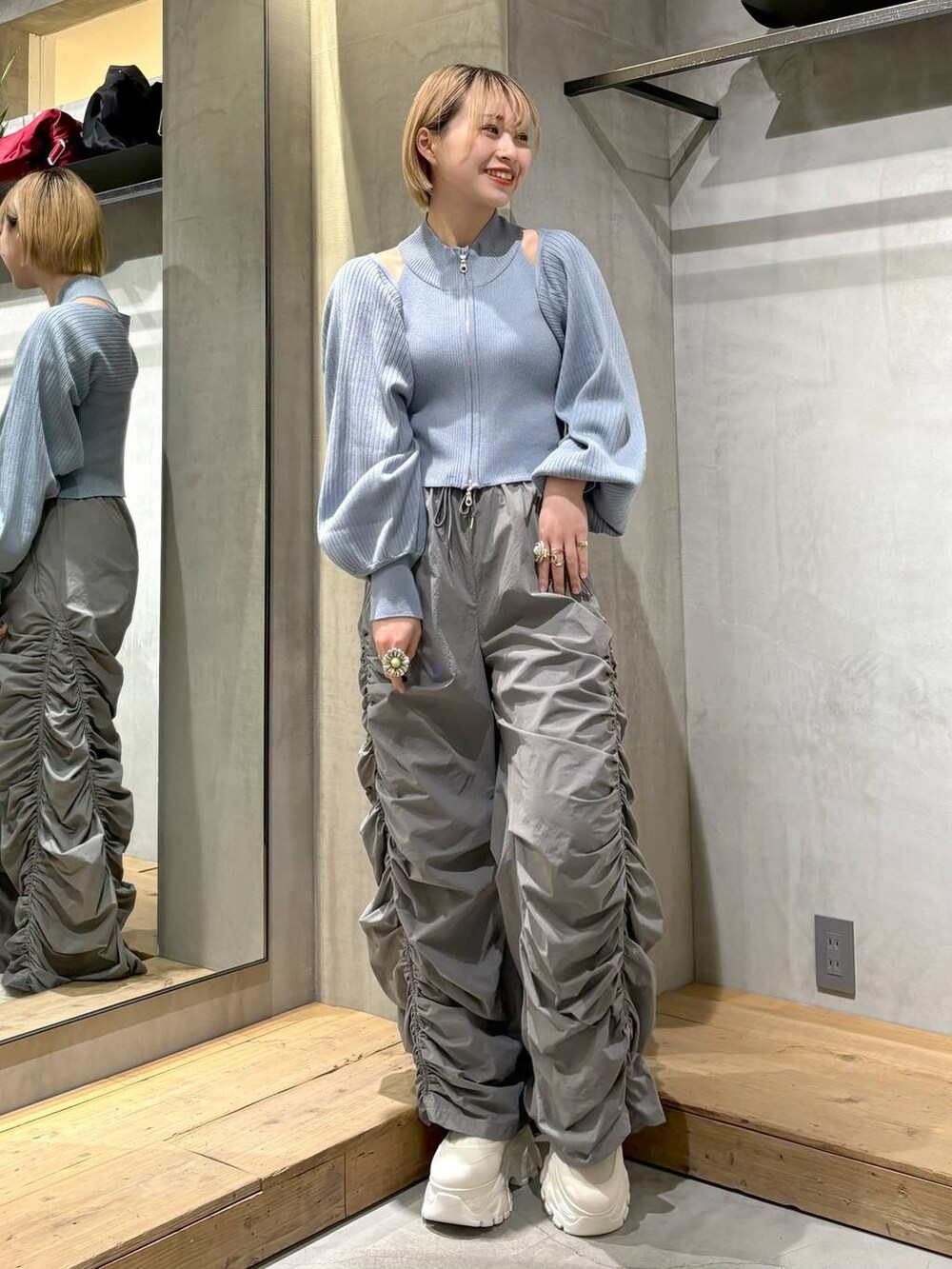 グレー系のその他パンツ、ホワイト系のスニーカー、ブルー系のニット/セーターを着用したレディースの春コーディネートの2枚目の写真