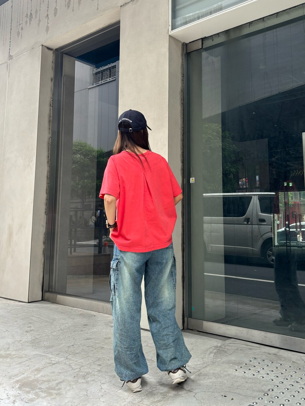 レッド系のTシャツ/カットソー、ブルー系のデニムパンツ、ブルー系のキャップを着用したレディースの夏コーディネートの2枚目の写真