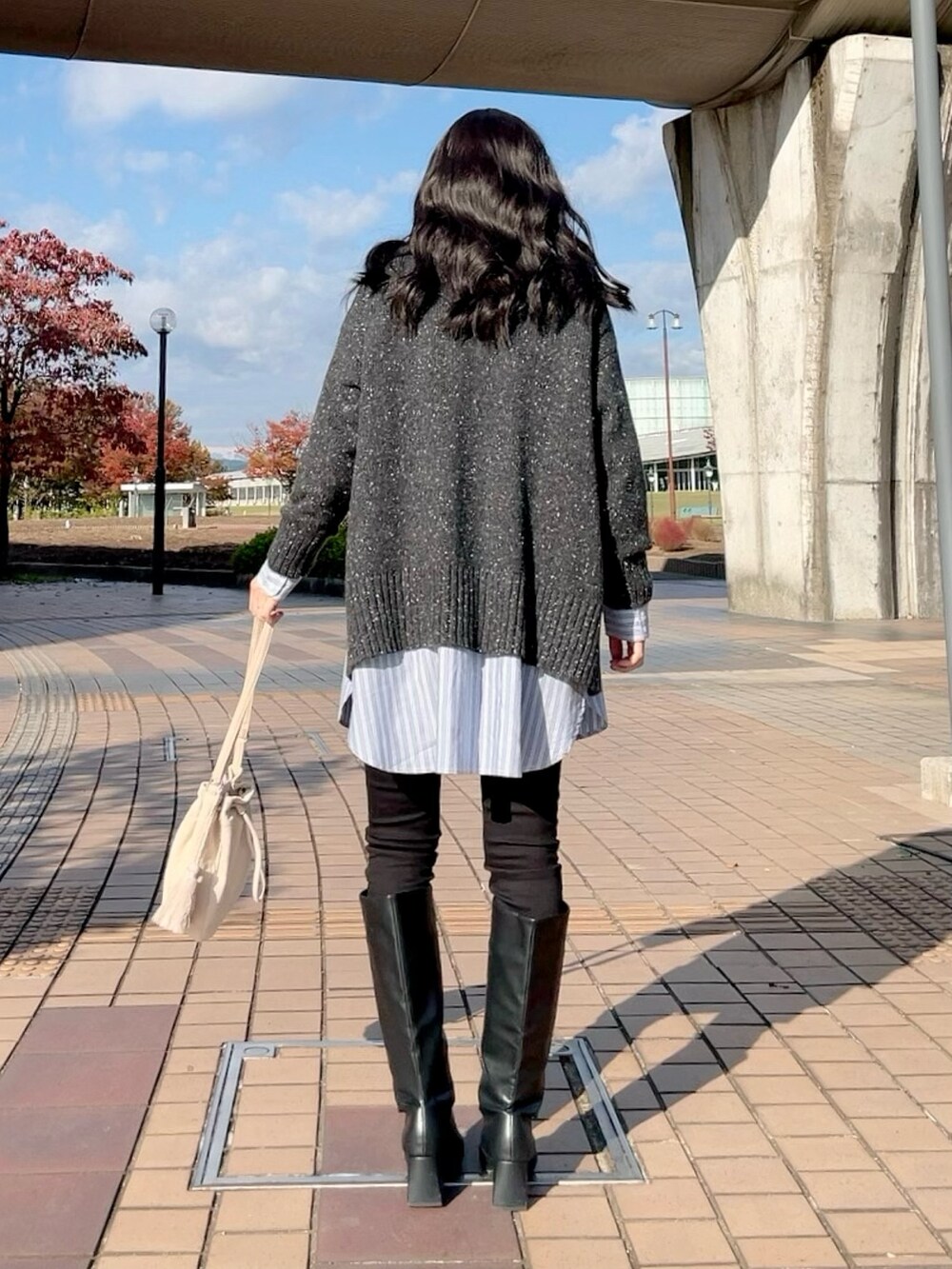 グレー系のニット/セーター、ブルー系のシャツ/ブラウス、ブラック系のデニムパンツを着用したレディースの冬コーディネートの3枚目の写真