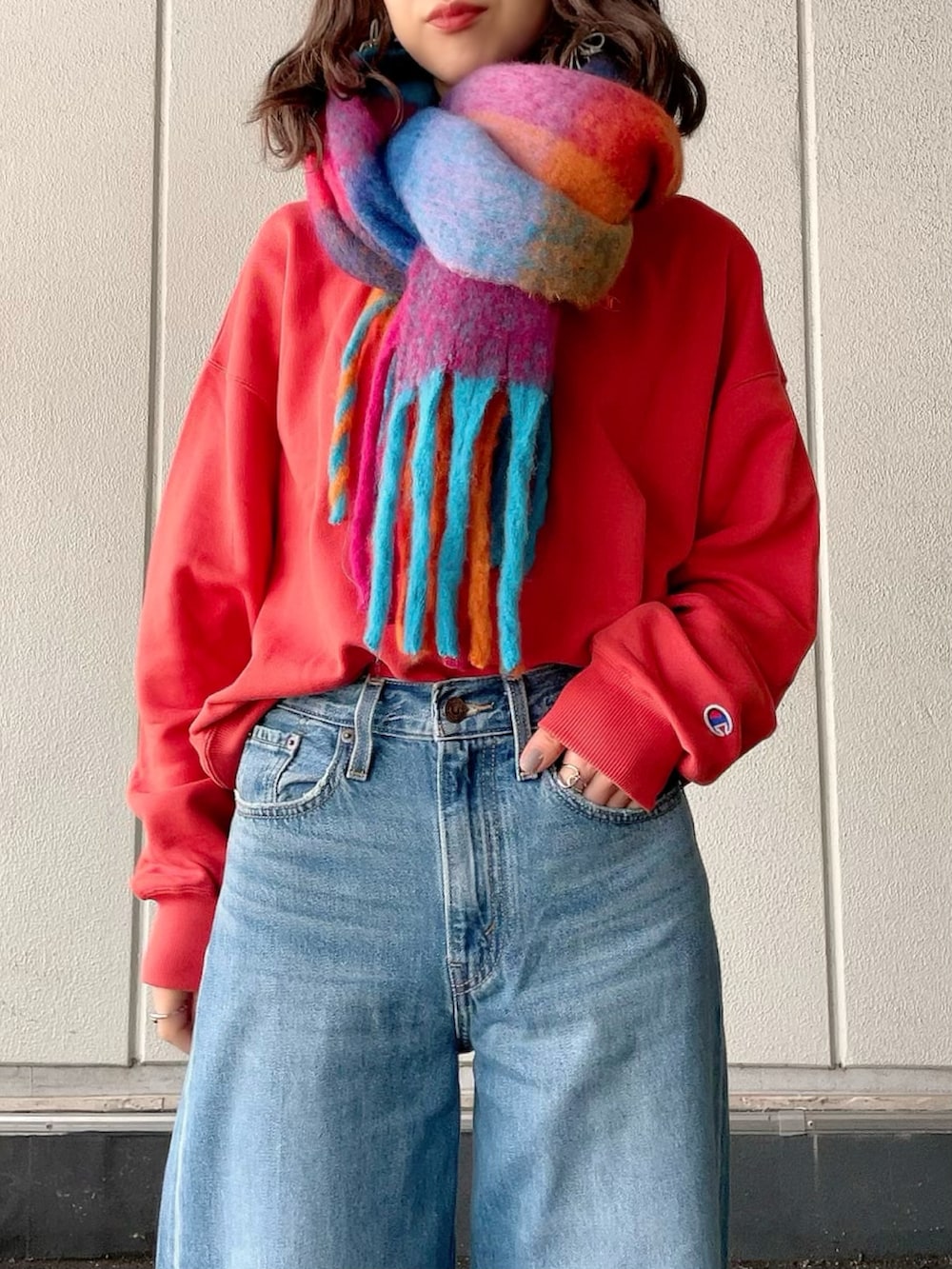 レッド系のスウェット、ブルー系のデニムパンツ、ブラック系のブーツを着用したレディースの冬コーディネートの4枚目の写真