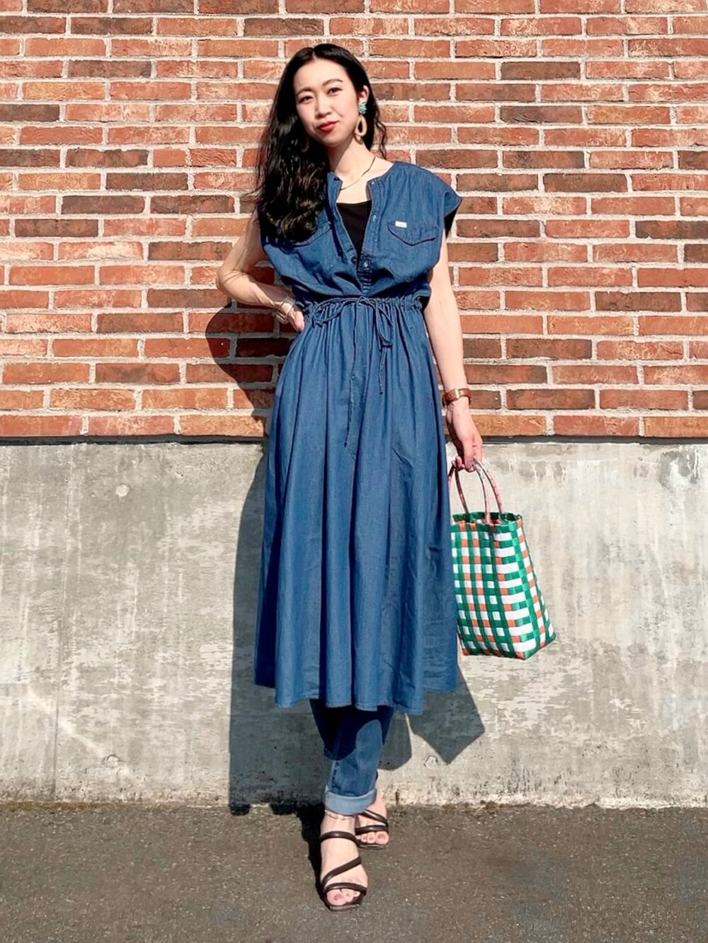 ブルー系のシャツワンピース、ブラック系のタンクトップ、ブルー系のデニムパンツを着用したレディースの夏コーディネートの2枚目の写真