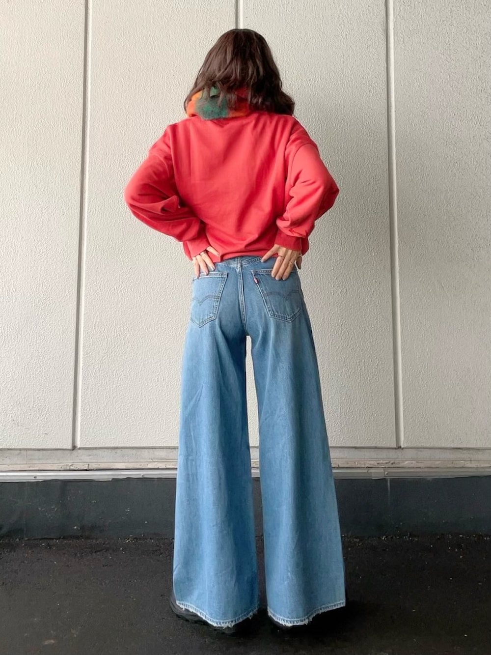 レッド系のスウェット、ブルー系のデニムパンツ、ブラック系のブーツを着用したレディースの冬コーディネートの3枚目の写真