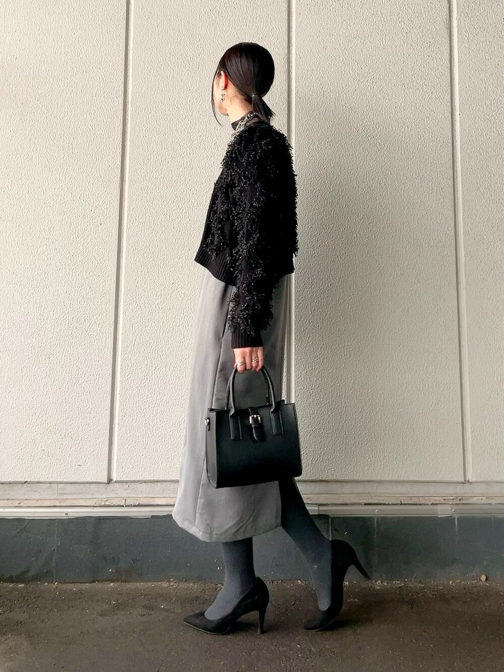 グレー系のワンピース、ブラック系のカーディガン/ボレロ、ブラック系のショルダーバッグを着用したレディースの冬コーディネートの3枚目の写真