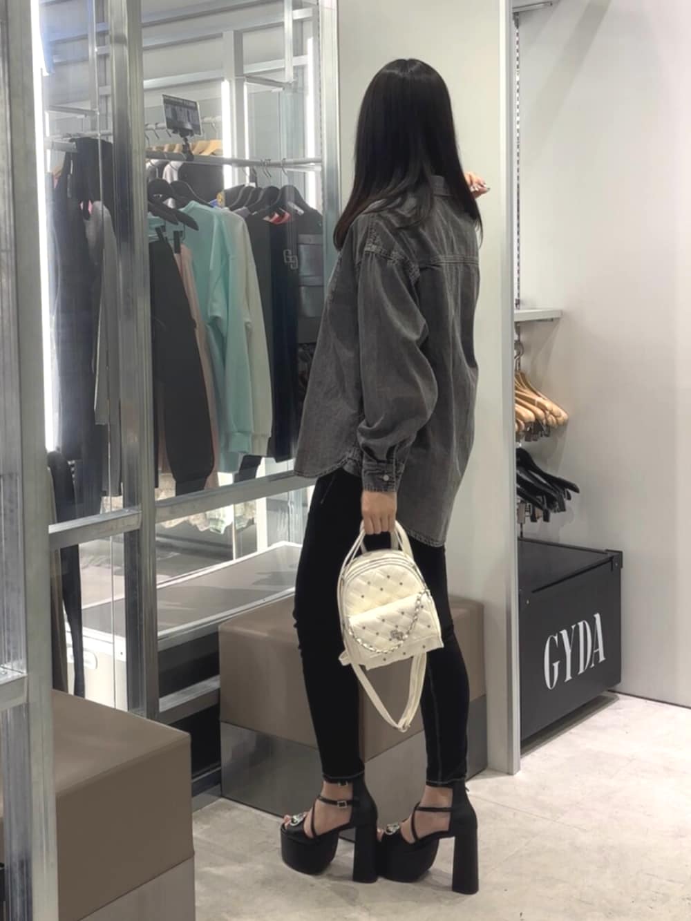 ブラック系のシャツ/ブラウス、ブラック系のデニムパンツ、ホワイト系のバックパック/リュックを着用したレディースの春コーディネートの2枚目の写真