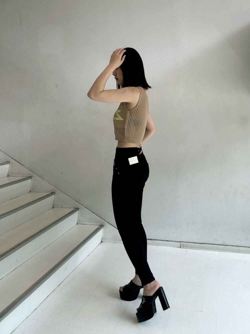 ブラック系のデニムパンツ、ベージュ系のタンクトップ、ブラック系のサンダルを着用したレディースの夏コーディネートの2枚目の写真