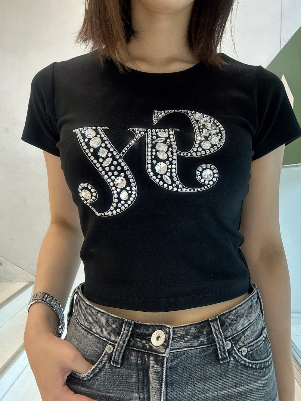 ブラック系のデニムスカート、ブラック系のTシャツ/カットソー、ホワイト系のサンダルを着用したレディースの夏コーディネートの4枚目の写真