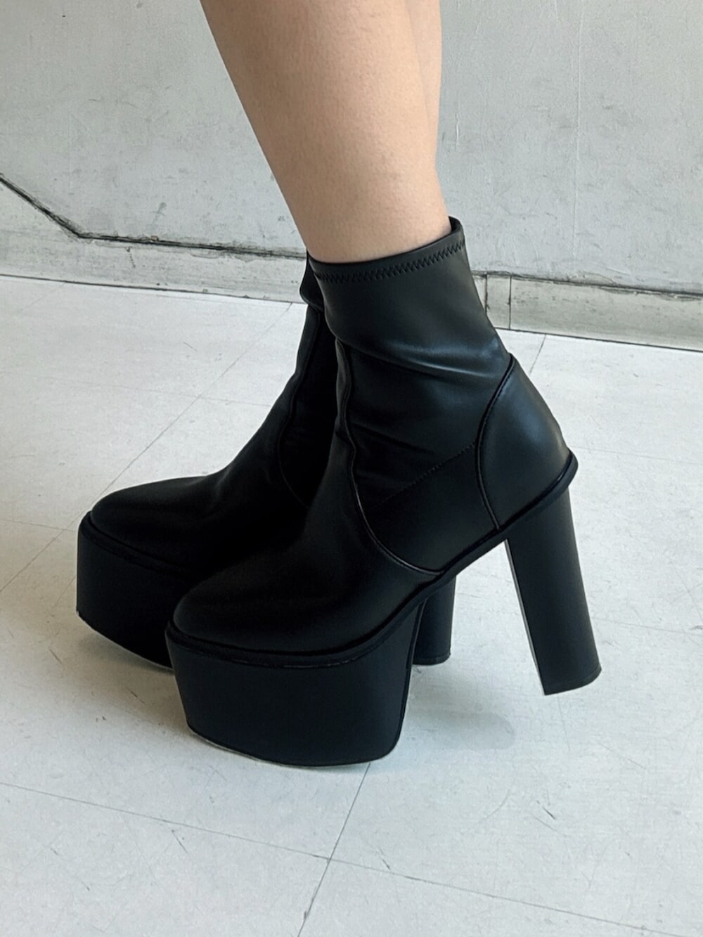 ブラック系のブーツ、ブラック系のダウンジャケット/コート、グレー系のワンピースを着用したレディースの秋コーディネートの5枚目の写真