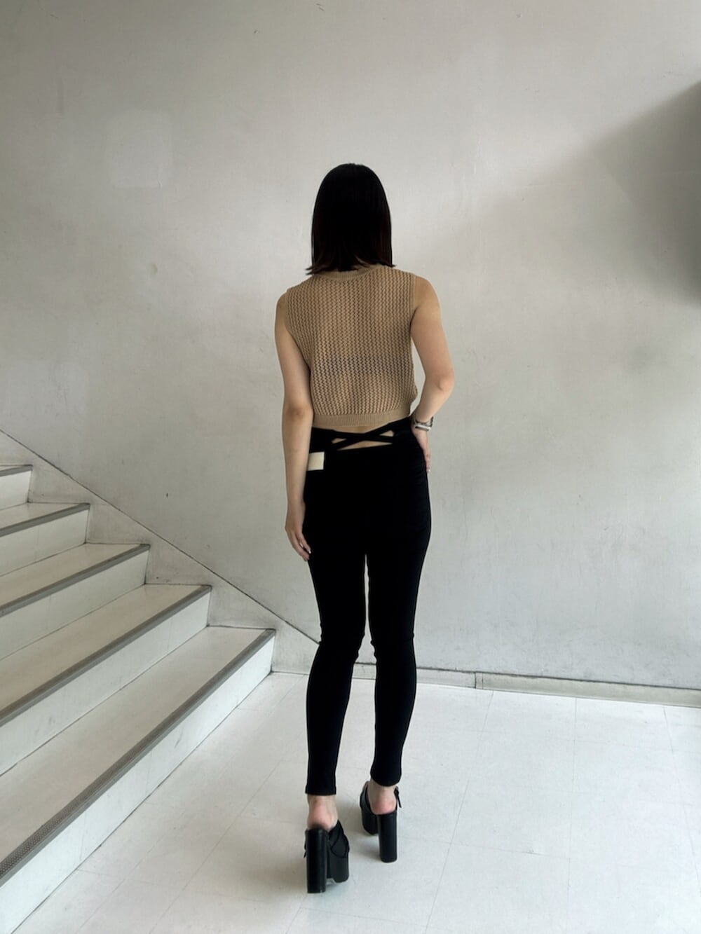 ブラック系のデニムパンツ、ベージュ系のタンクトップ、ブラック系のサンダルを着用したレディースの夏コーディネートの3枚目の写真