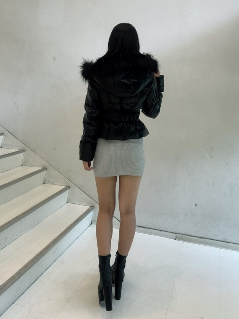 ブラック系のブーツ、ブラック系のダウンジャケット/コート、グレー系のワンピースを着用したレディースの秋コーディネートの3枚目の写真