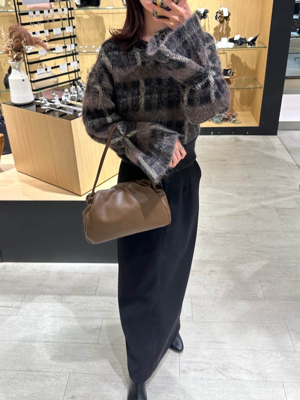 ブラック系のスカート、ブラウン系のショルダーバッグ、ブラック系のニット/セーターを着用したレディースの秋コーディネートの3枚目の写真