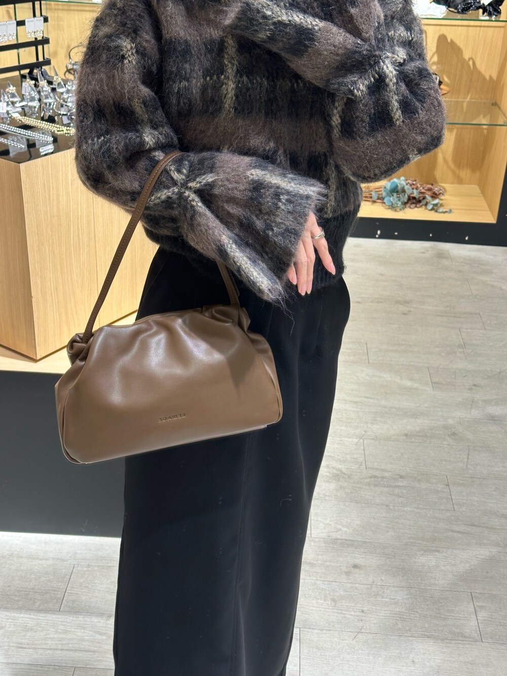 ブラック系のスカート、ブラウン系のショルダーバッグ、ブラック系のニット/セーターを着用したレディースの秋コーディネートの4枚目の写真