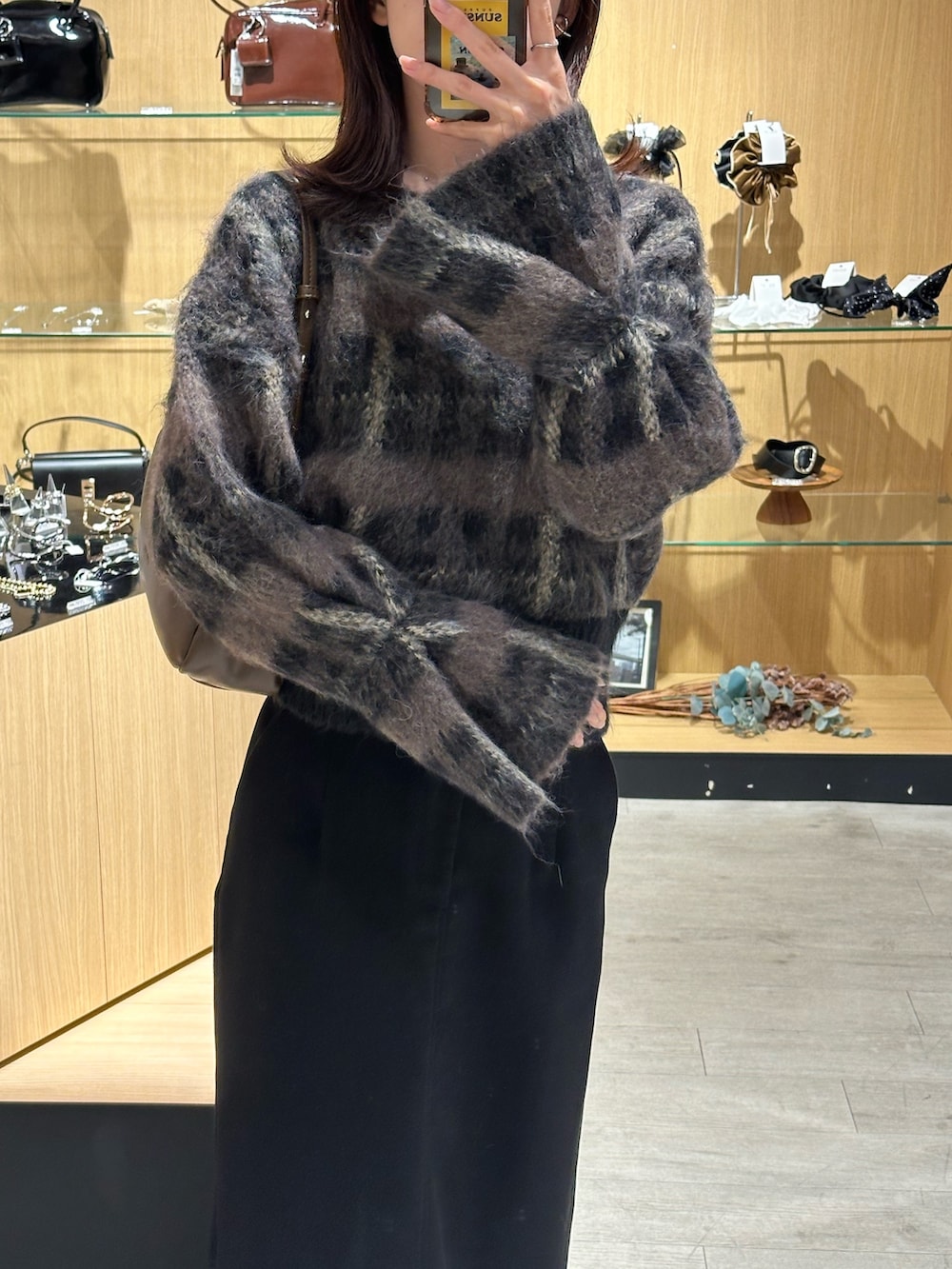 ブラック系のスカート、ブラウン系のショルダーバッグ、ブラック系のニット/セーターを着用したレディースの秋コーディネートの2枚目の写真