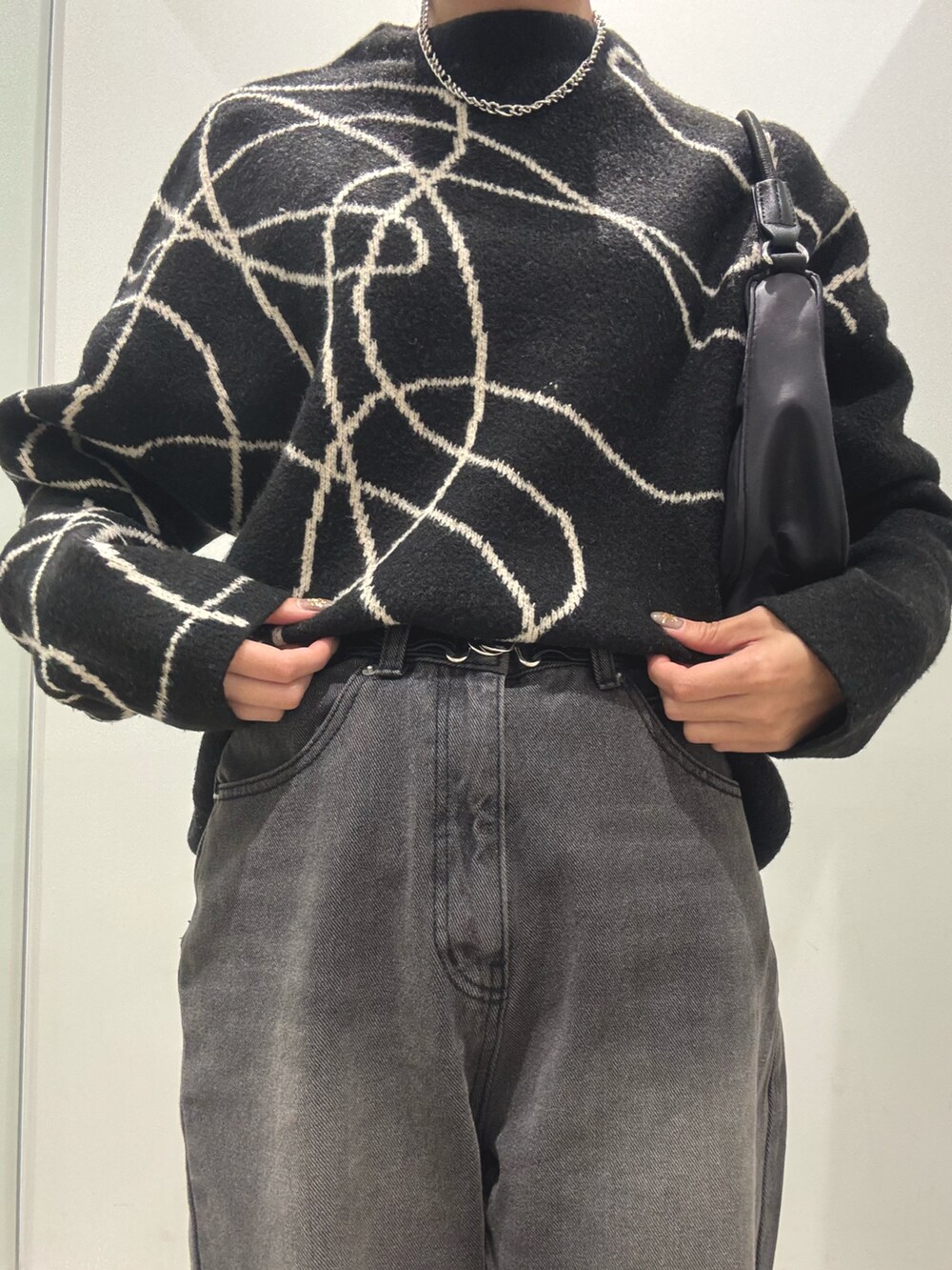 ブラック系のニット/セーター、ブラック系のハンドバッグ、ブラック系のデニムパンツを着用したレディースの秋コーディネートの2枚目の写真