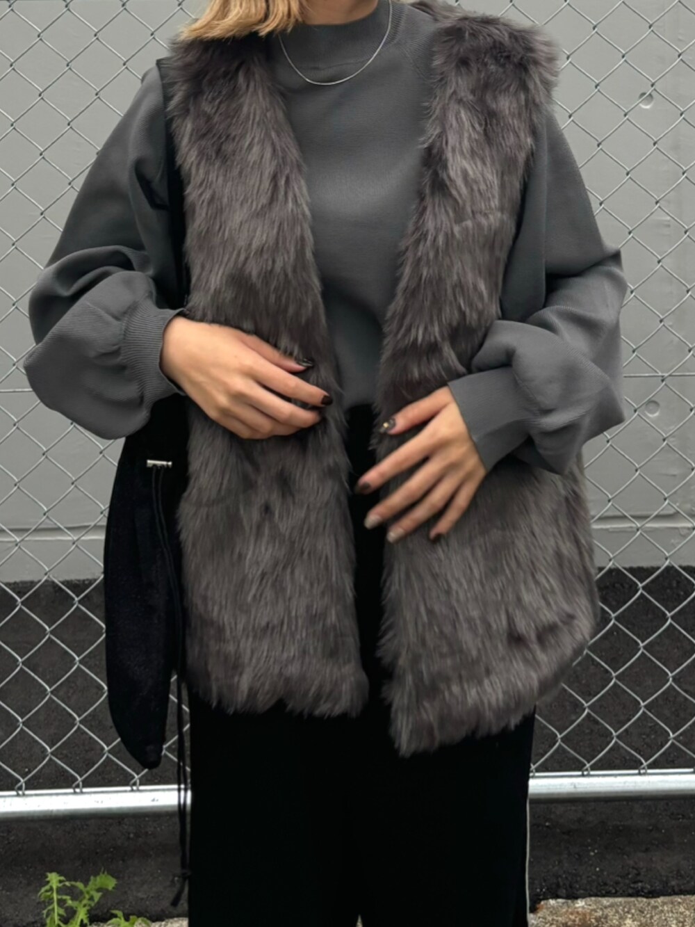 グレー系のベスト、グレー系のニット/セーター、ブラック系のトートバッグを着用したレディースの秋コーディネートの2枚目の写真