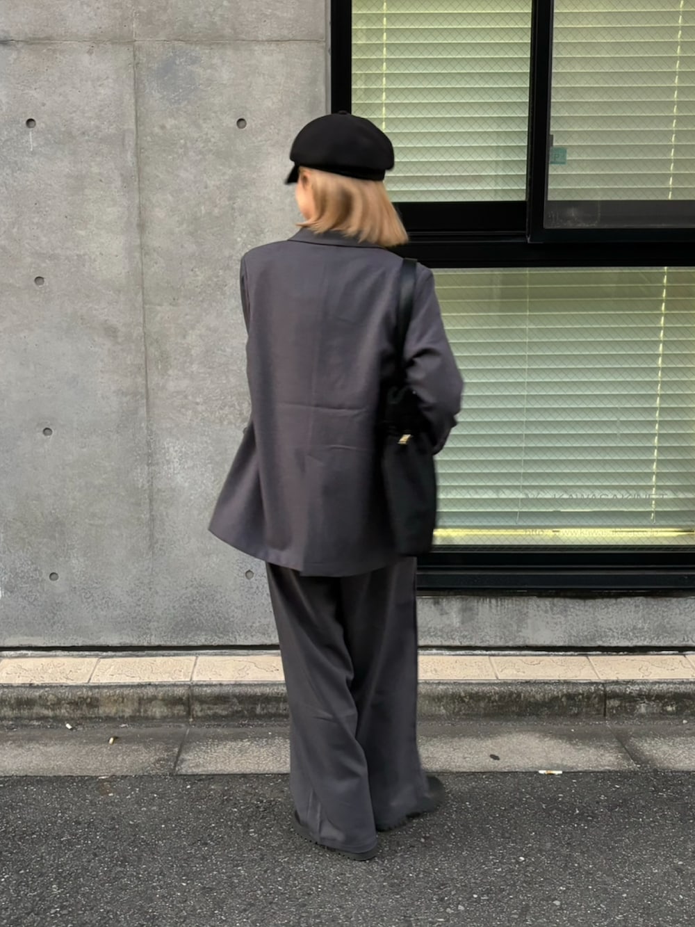 グレー系のスラックス、グレー系のテーラードジャケット、ブラック系のトートバッグを着用したレディースの秋コーディネートの3枚目の写真