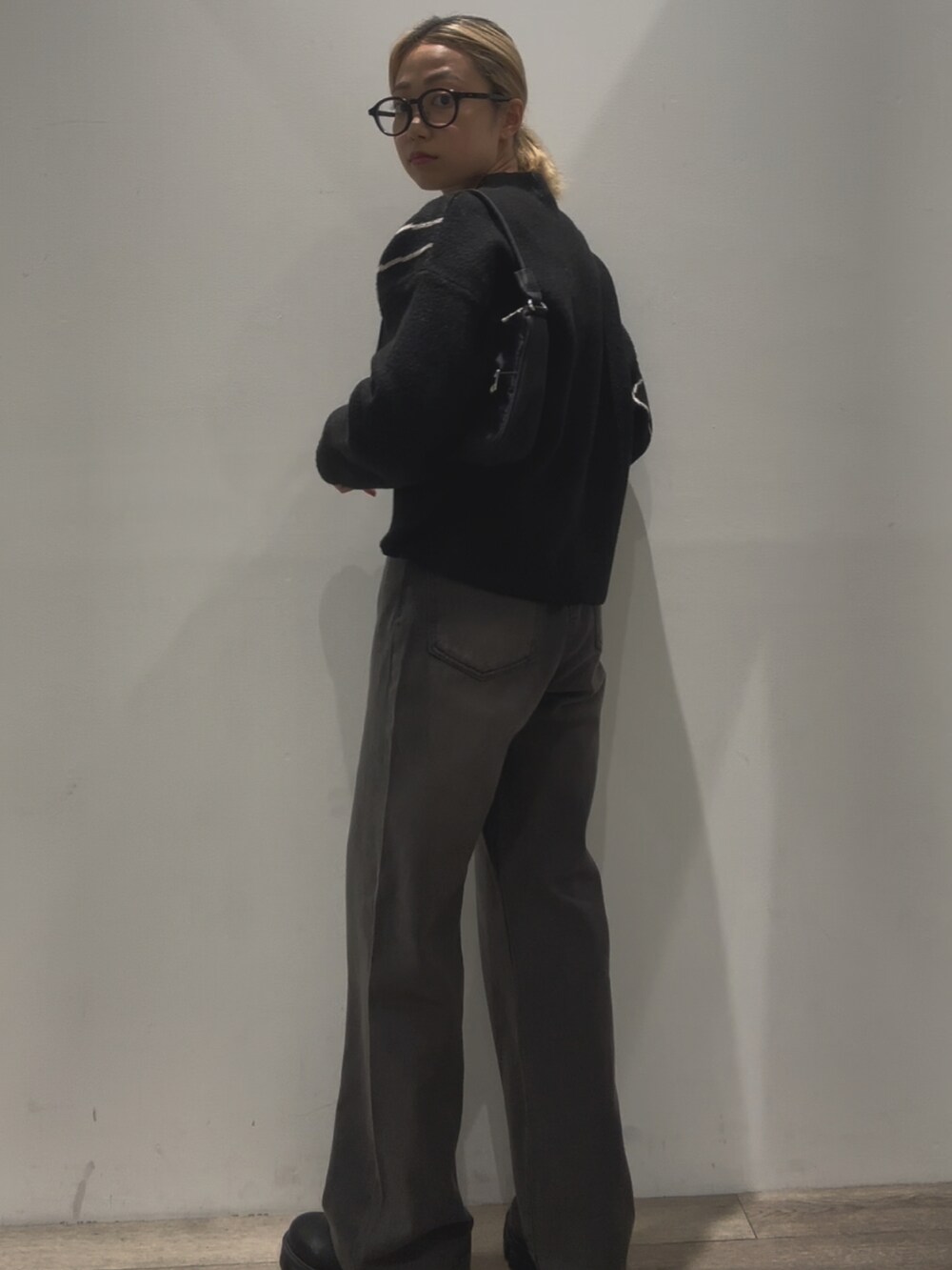 ブラック系のニット/セーター、ブラック系のハンドバッグ、ブラック系のデニムパンツを着用したレディースの秋コーディネートの4枚目の写真