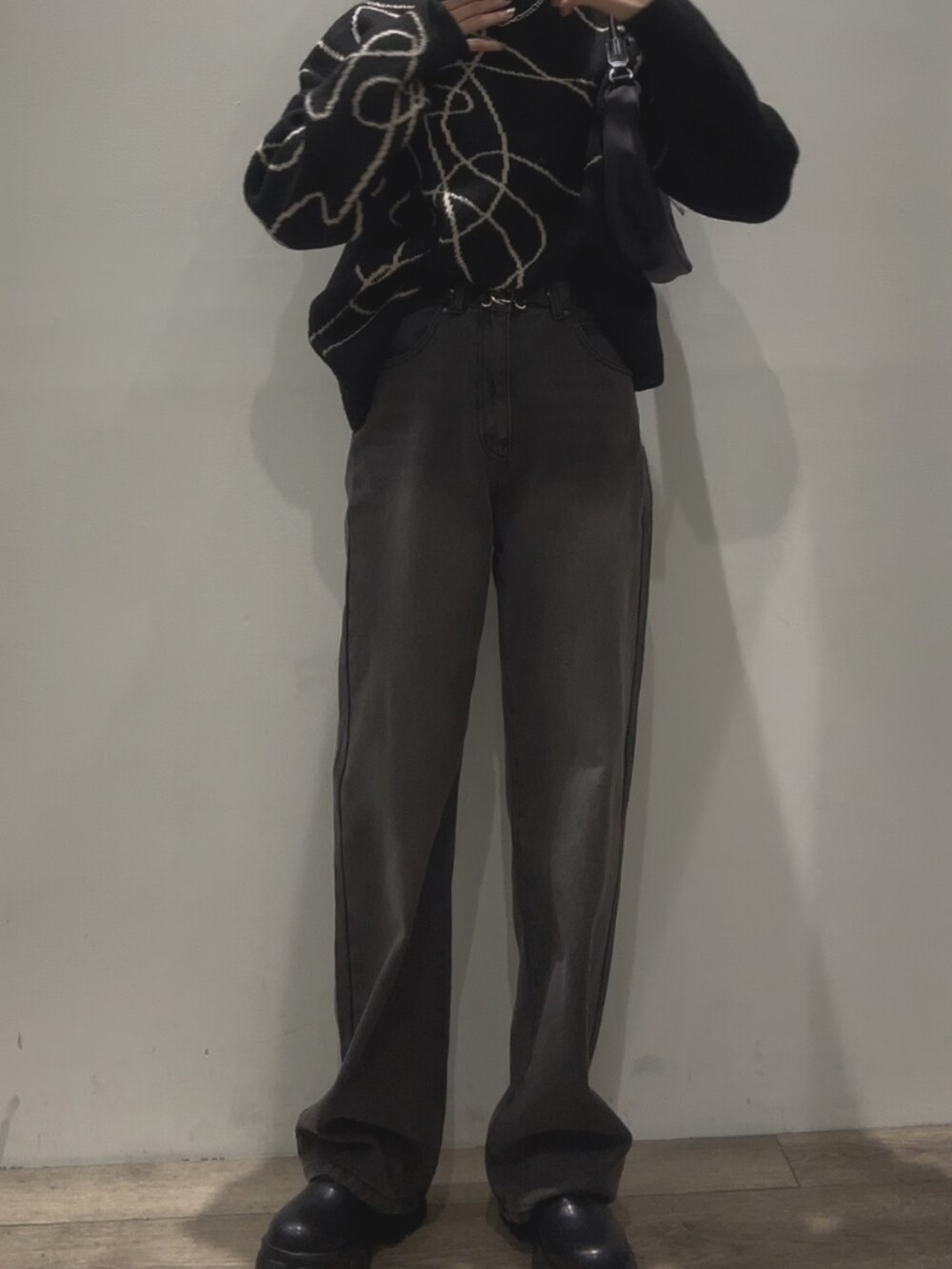 ブラック系のニット/セーター、ブラック系のハンドバッグ、ブラック系のデニムパンツを着用したレディースの秋コーディネートの3枚目の写真