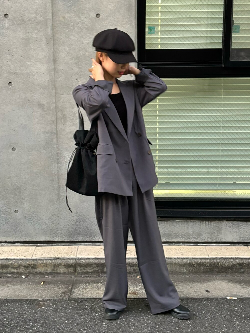 グレー系のスラックス、グレー系のテーラードジャケット、ブラック系のトートバッグを着用したレディースの秋コーディネートの4枚目の写真
