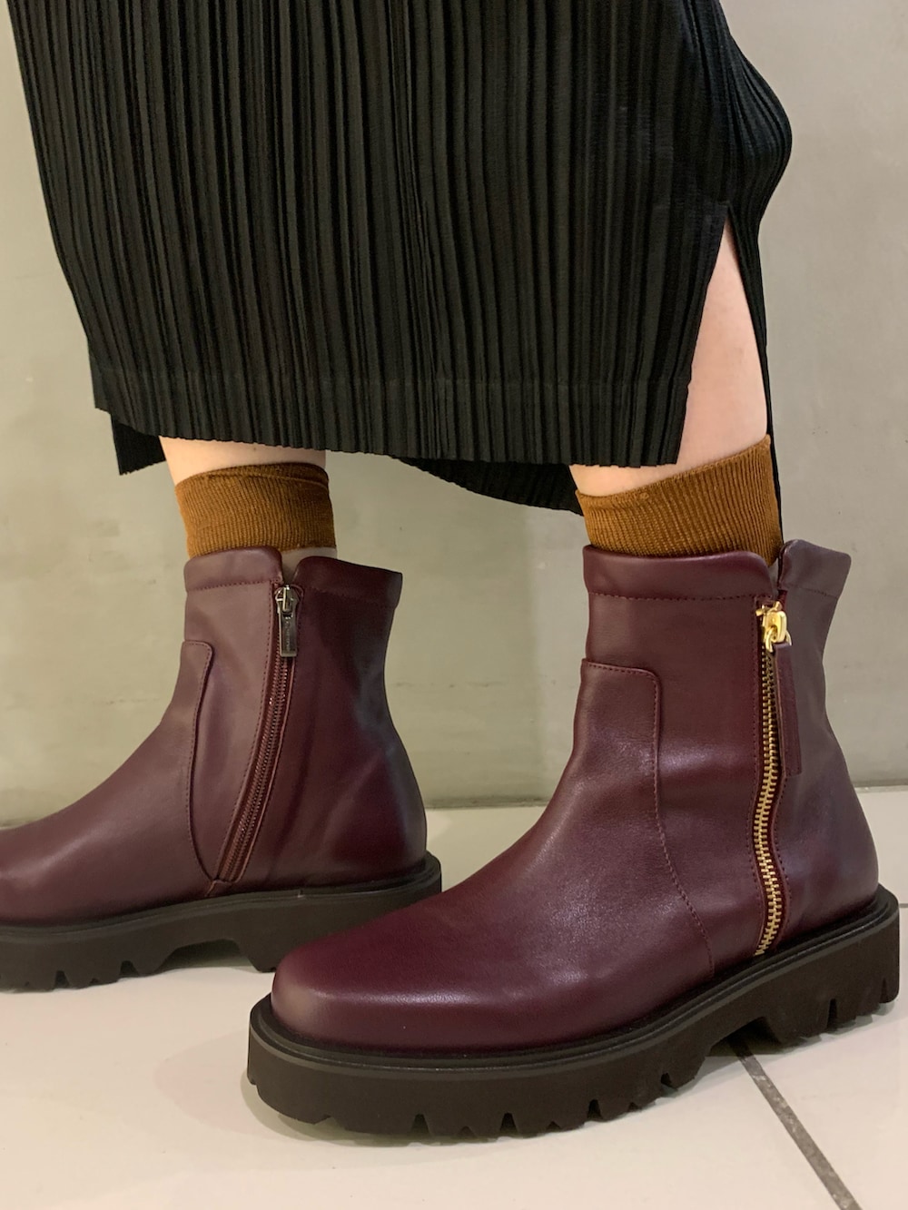 レッド系のブーツを着用したレディースの秋コーディネートの2枚目の写真