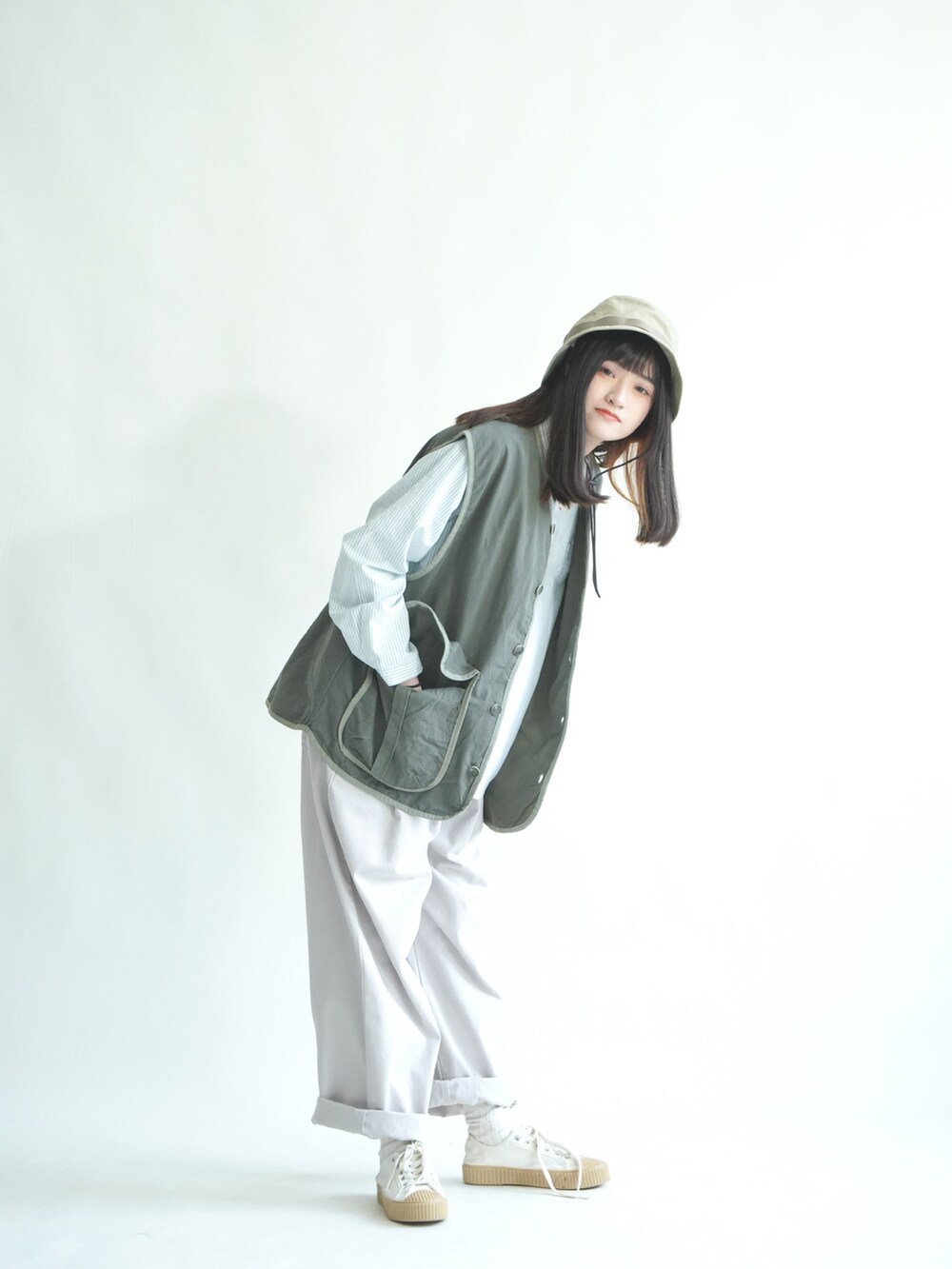 グリーン系のトップス、グレー系のパンツを着用したレディースの春コーディネートの2枚目の写真