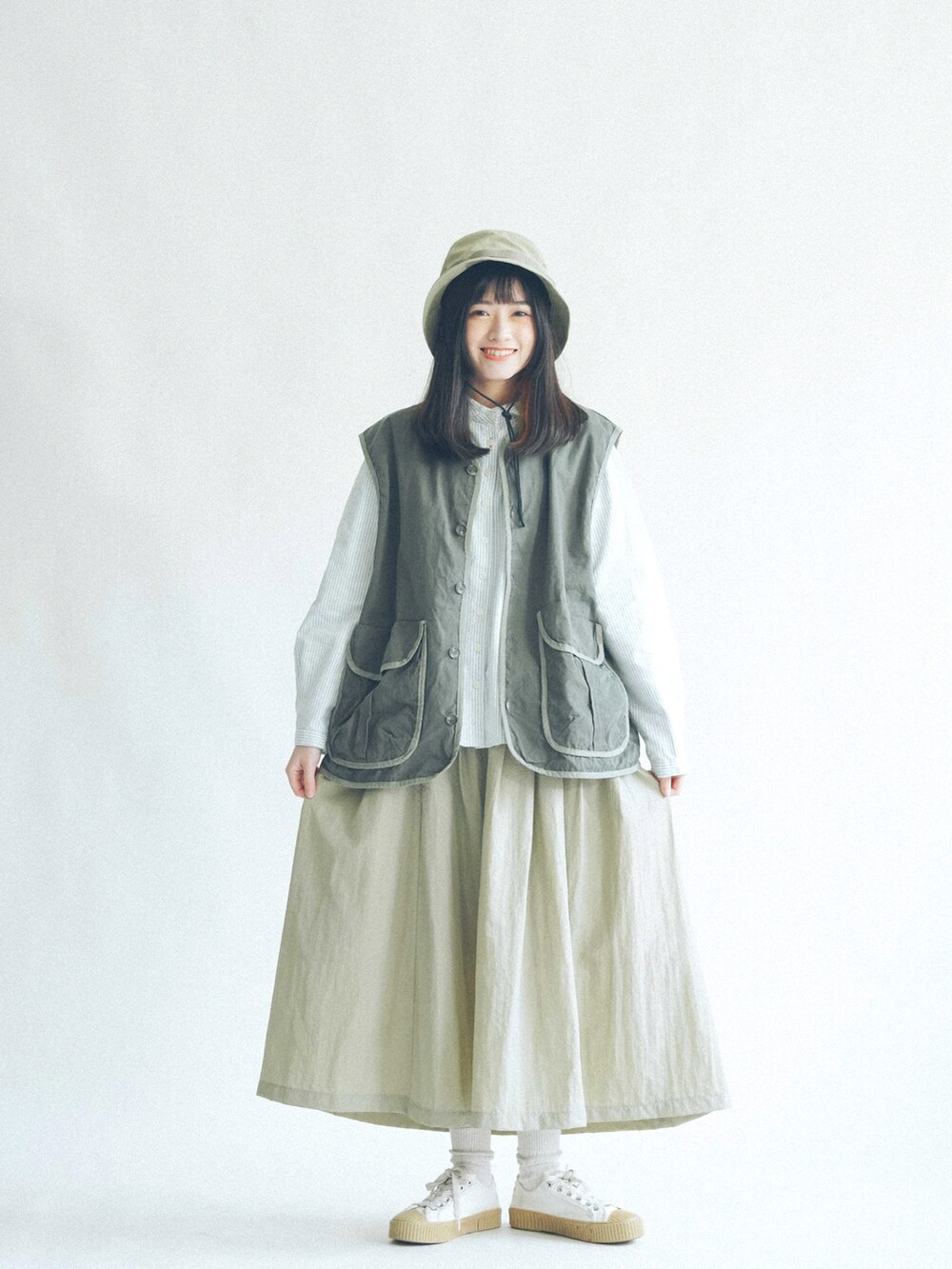 グリーン系のトップス、グレー系のパンツを着用したレディースの春コーディネートの3枚目の写真