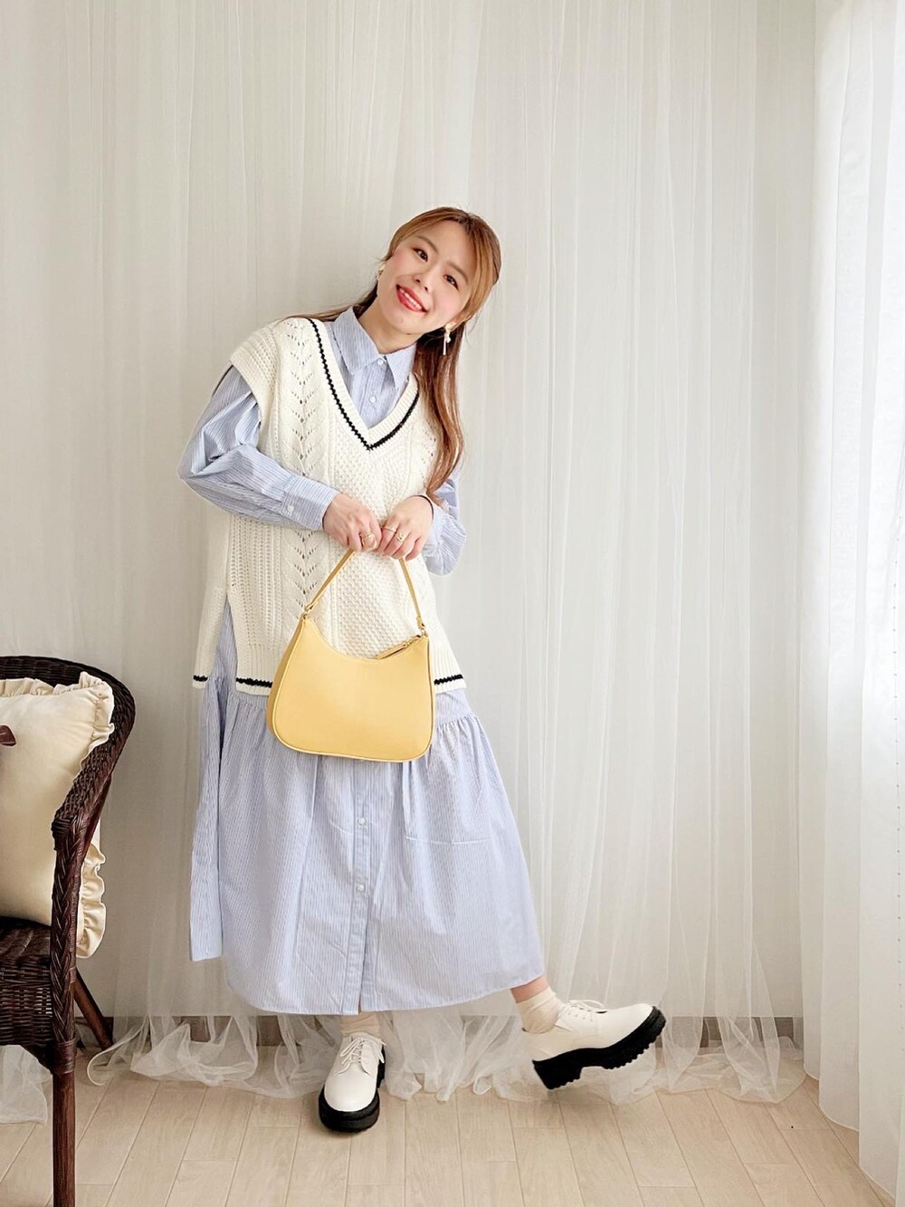 ホワイト系のベスト、ブルー系のシャツワンピース、イエロー系のショルダーバッグを着用したレディースの春コーディネートの2枚目の写真
