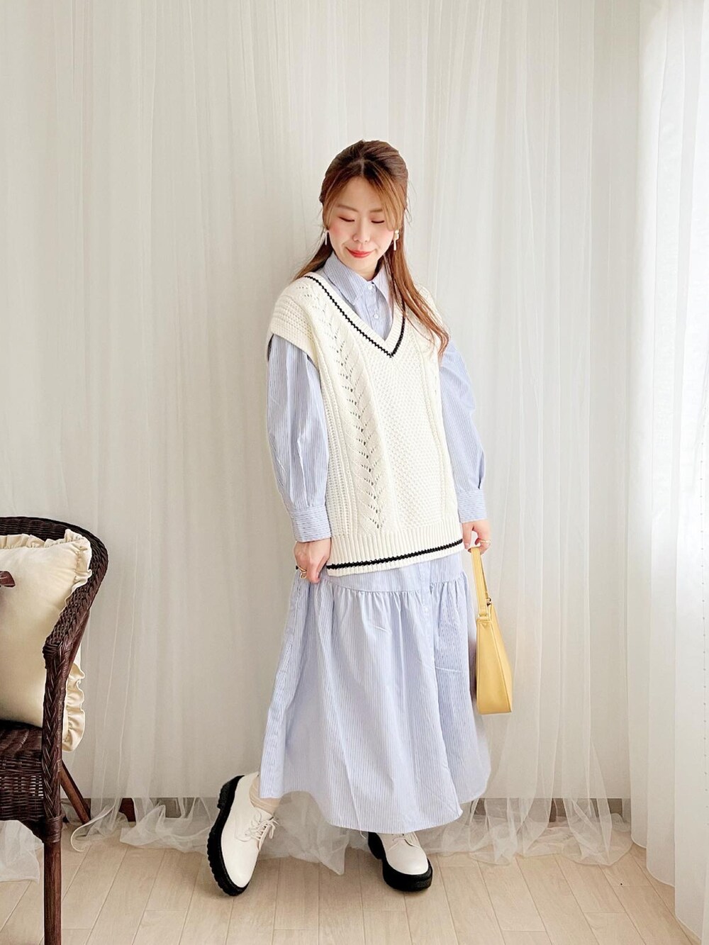 ホワイト系のベスト、ブルー系のシャツワンピース、イエロー系のショルダーバッグを着用したレディースの春コーディネートの3枚目の写真