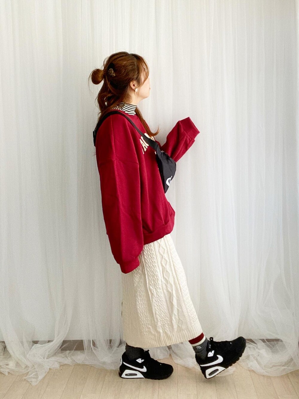 レッド系のスウェット、ホワイト系のスカート、ブラック系のスニーカーを着用したレディースの冬コーディネートの2枚目の写真